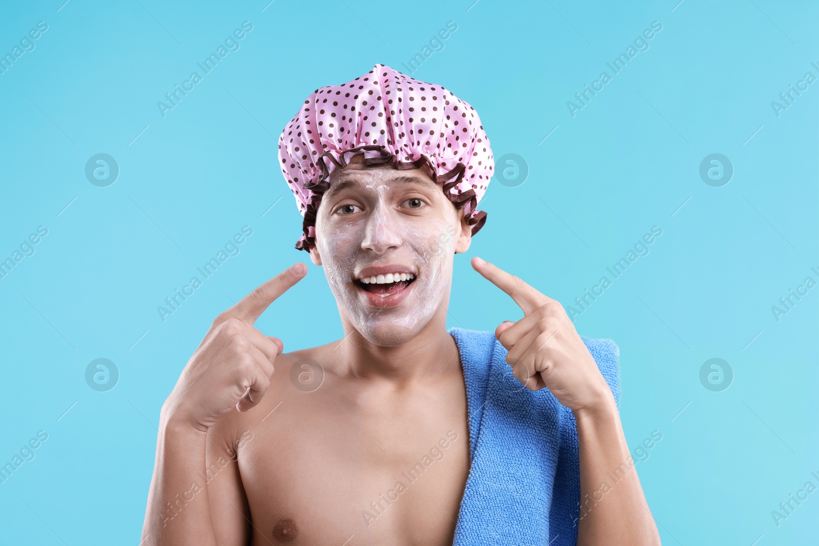 Photo of Man in shower cap with cream on his face against light blue background