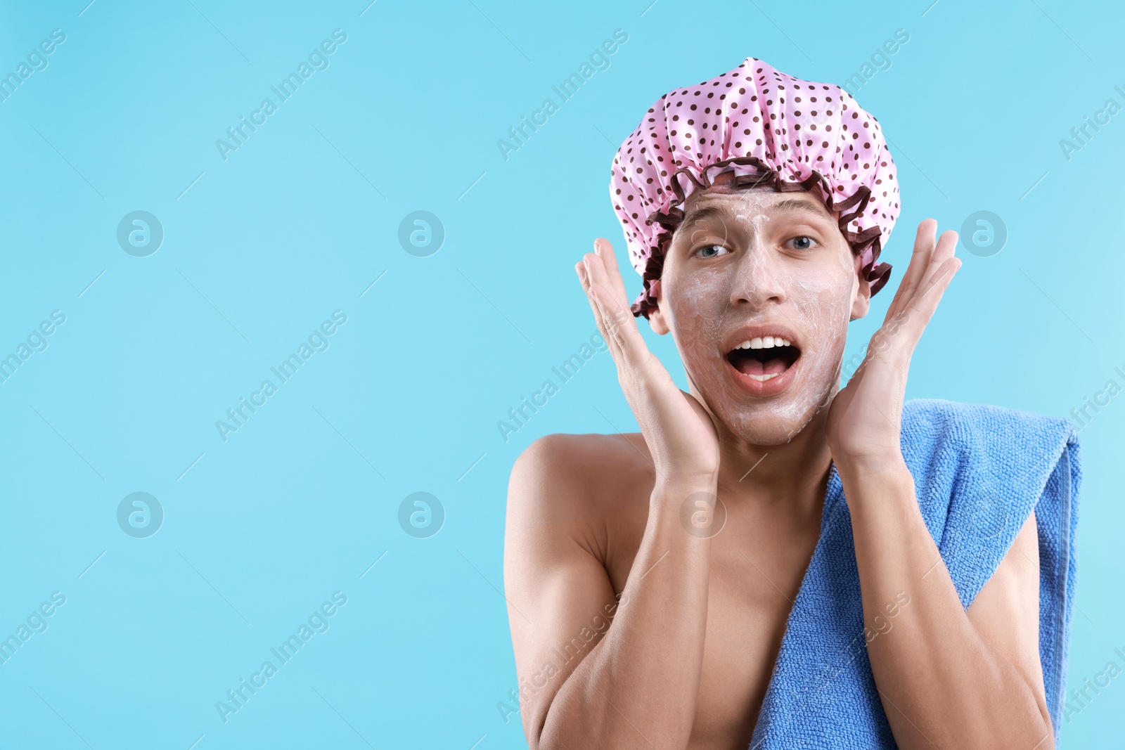 Photo of Man in shower cap with cream on his face against light blue background, space for text