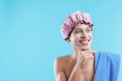 Photo of Man in shower cap with cream on his face against light blue background, space for text