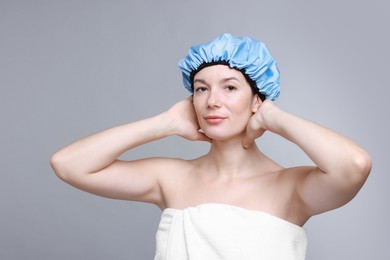 Woman wearing shower cap on grey background