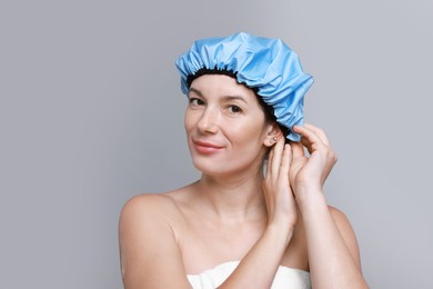 Woman wearing shower cap on grey background