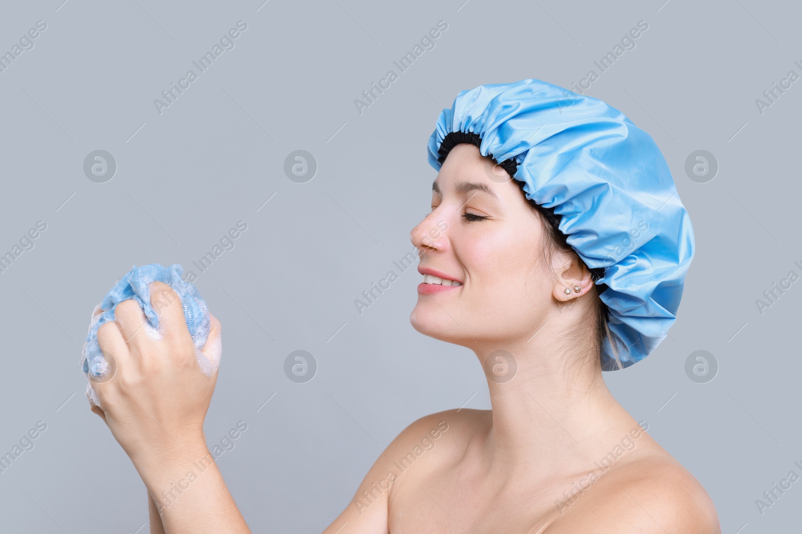 Photo of Woman with shower cap and mesh sponge on grey background