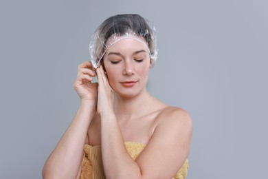 Woman wearing shower cap on grey background