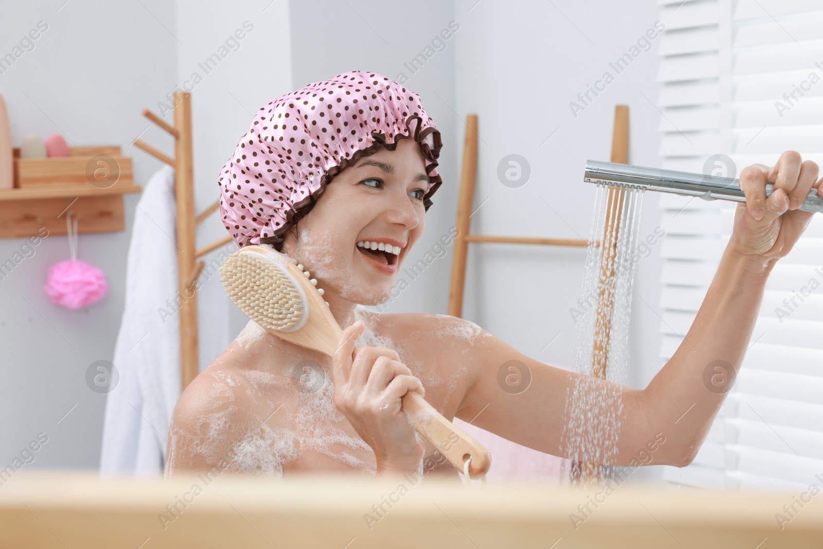 Photo of Woman with cap and brush taking shower in bathroom