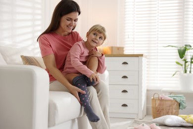 Mother helping her daughter to put tights on at home. Space for text