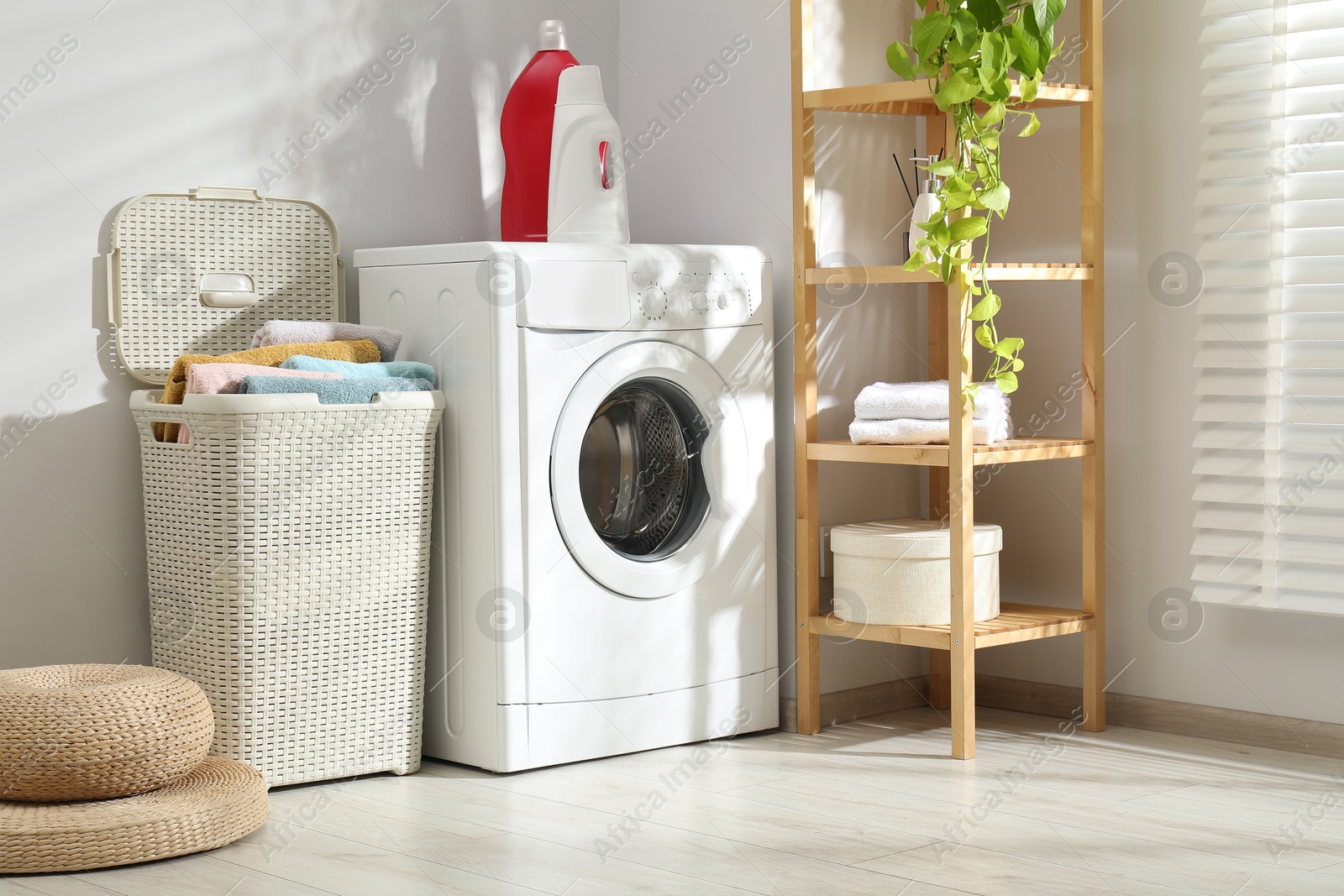 Photo of Wicker basket full of laundry, washing machine and detergents in bathroom