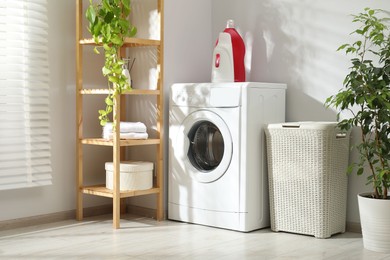 Photo of Wicker laundry basket, washing machine and detergents in bathroom