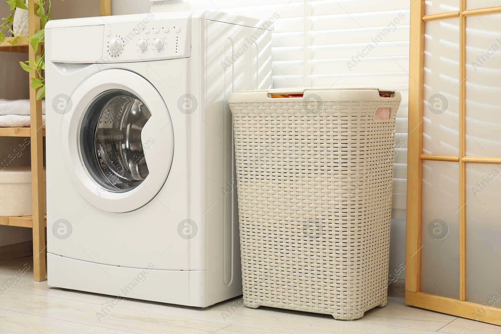 Photo of Wicker laundry basket and washing machine in bathroom