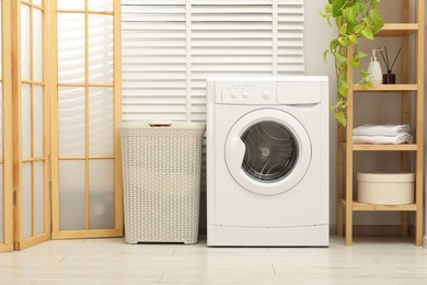 Photo of Wicker laundry basket and washing machine in bathroom