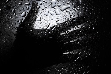 Silhouette of woman behind wet glass, closeup