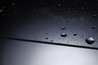 Photo of Water drops on grey glass surface, closeup