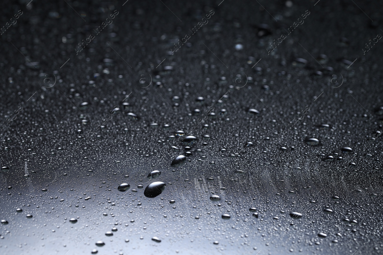 Photo of Water drops on dark glass surface, closeup