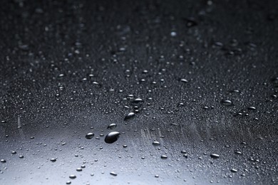 Water drops on dark glass surface, closeup