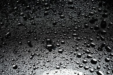 Photo of Water drops on dark glass surface, closeup