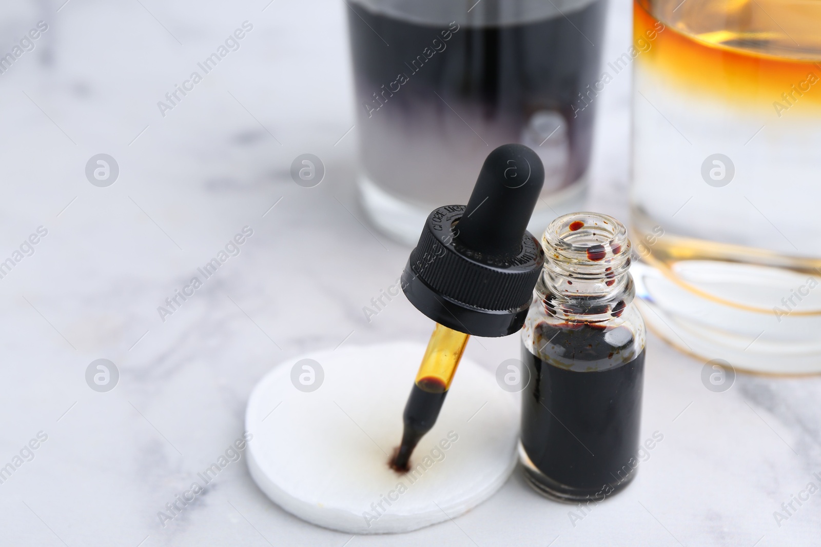 Photo of Bottle of aqueous iodine and glasses with liquids of different colors on white marble table, selective focus. Space for text