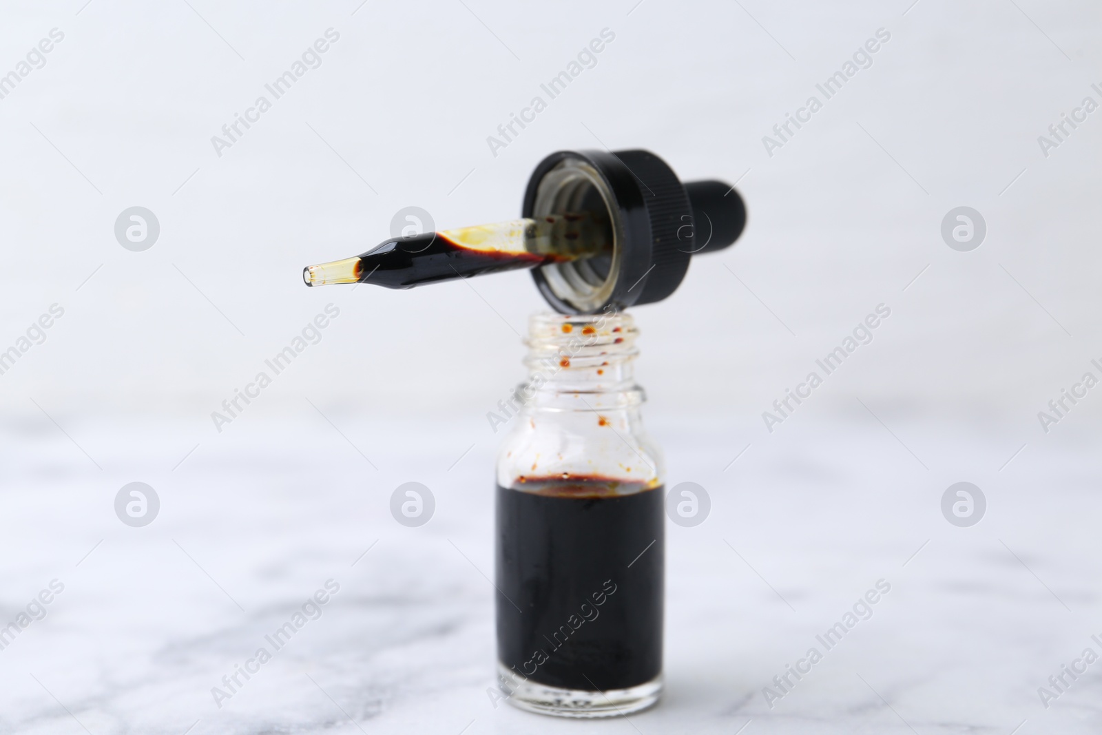 Photo of Bottle of aqueous iodine with pipette on white marble table, closeup