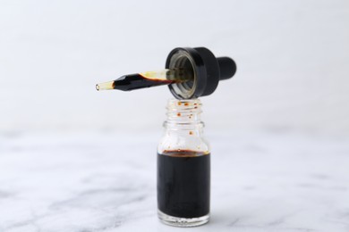 Photo of Bottle of aqueous iodine with pipette on white marble table, closeup