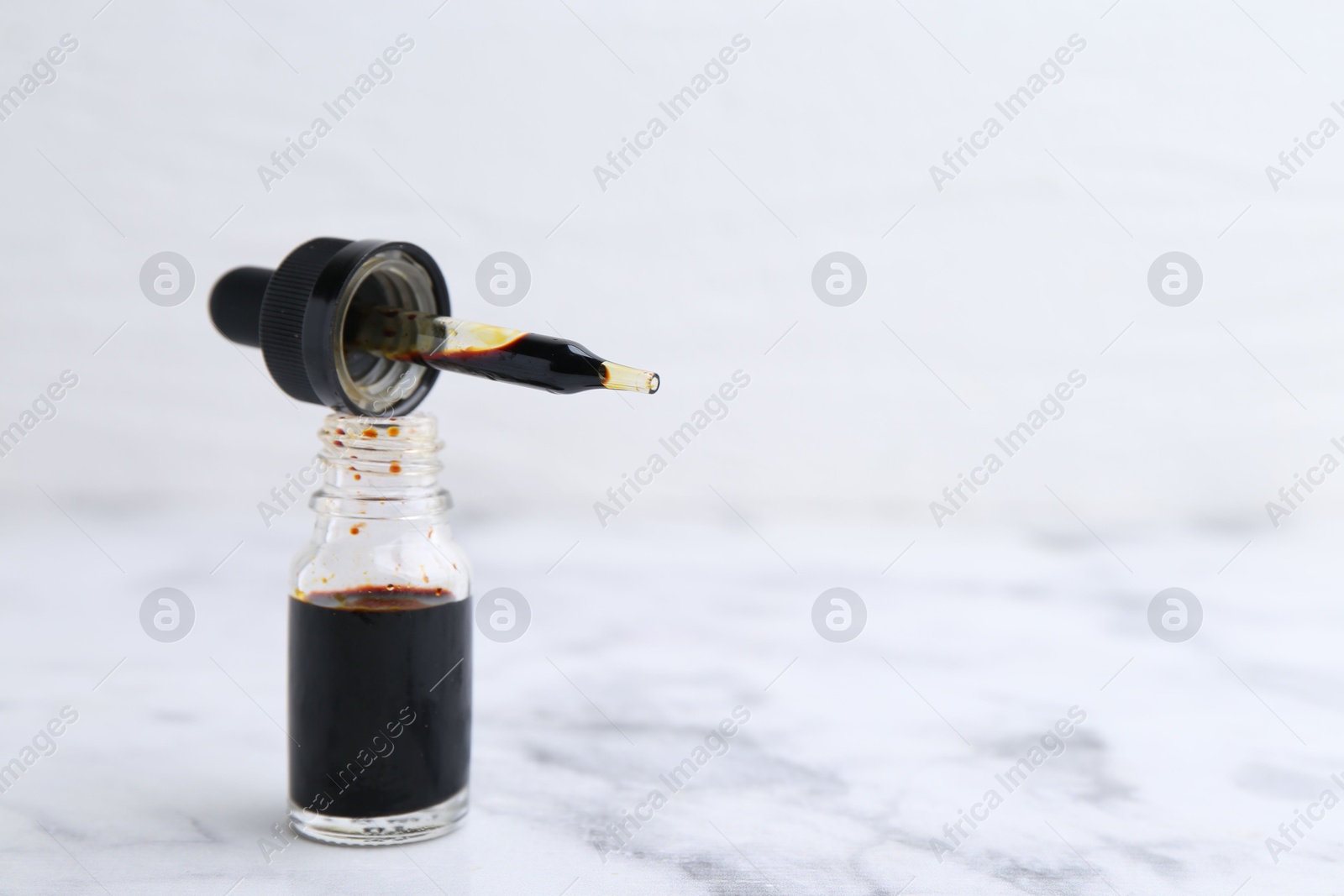 Photo of Bottle of aqueous iodine with pipette on white marble table, closeup. Space for text