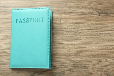 Photo of Passport in turquoise cover on wooden table, top view. Space for text