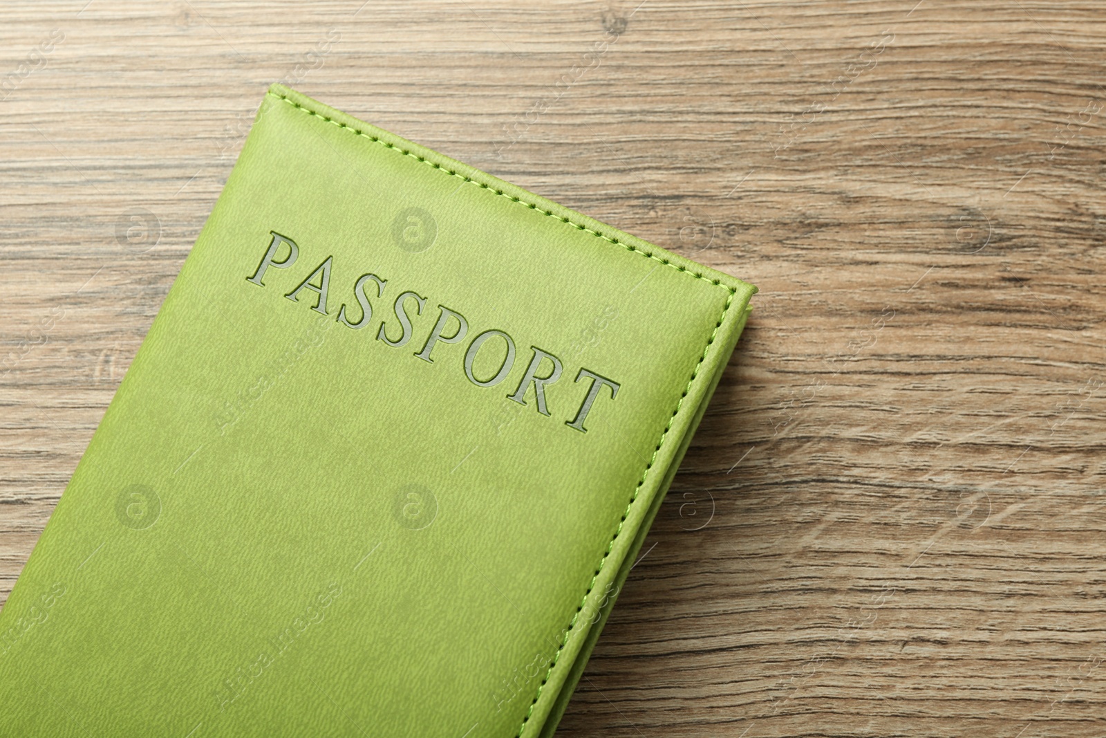 Photo of Passport in green cover on wooden table, top view. Space for text