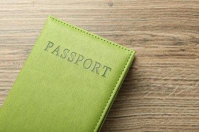 Photo of Passport in green cover on wooden table, top view. Space for text