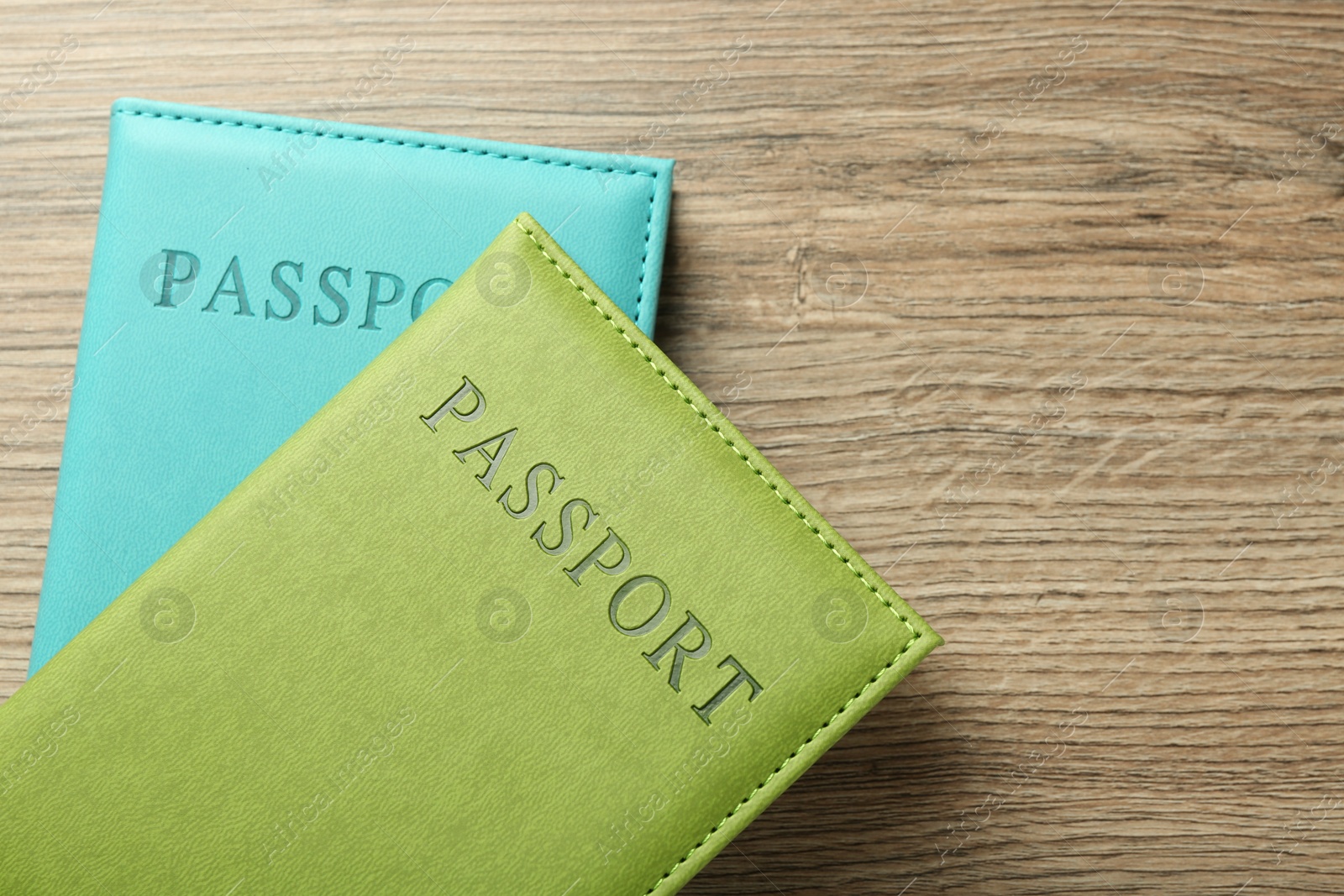 Photo of Two passports in bright covers on wooden table, top view. Space for text