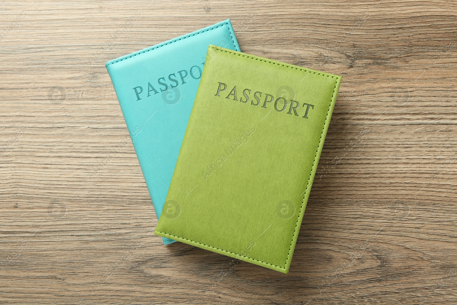 Photo of Two passports in bright covers on wooden table, top view