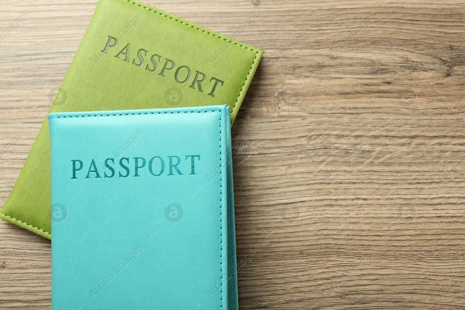 Photo of Two passports in bright covers on wooden table, top view. Space for text