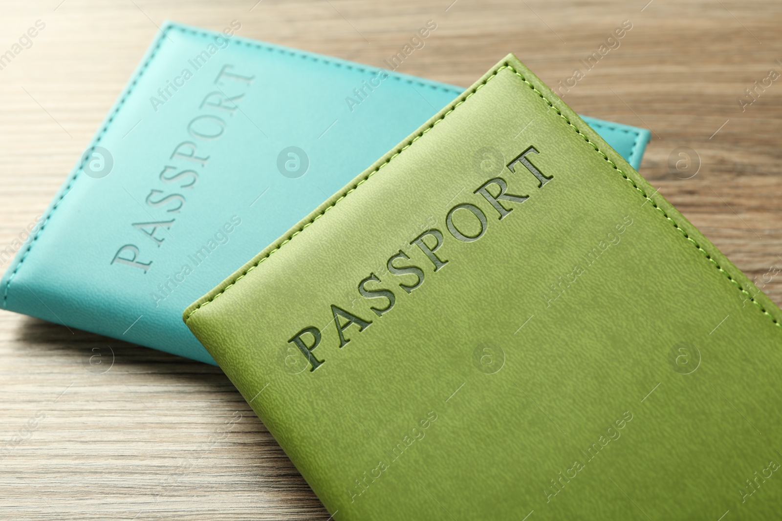 Photo of Two passports in bright covers on wooden table, closeup