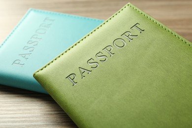 Photo of Two passports in bright covers on wooden table, closeup