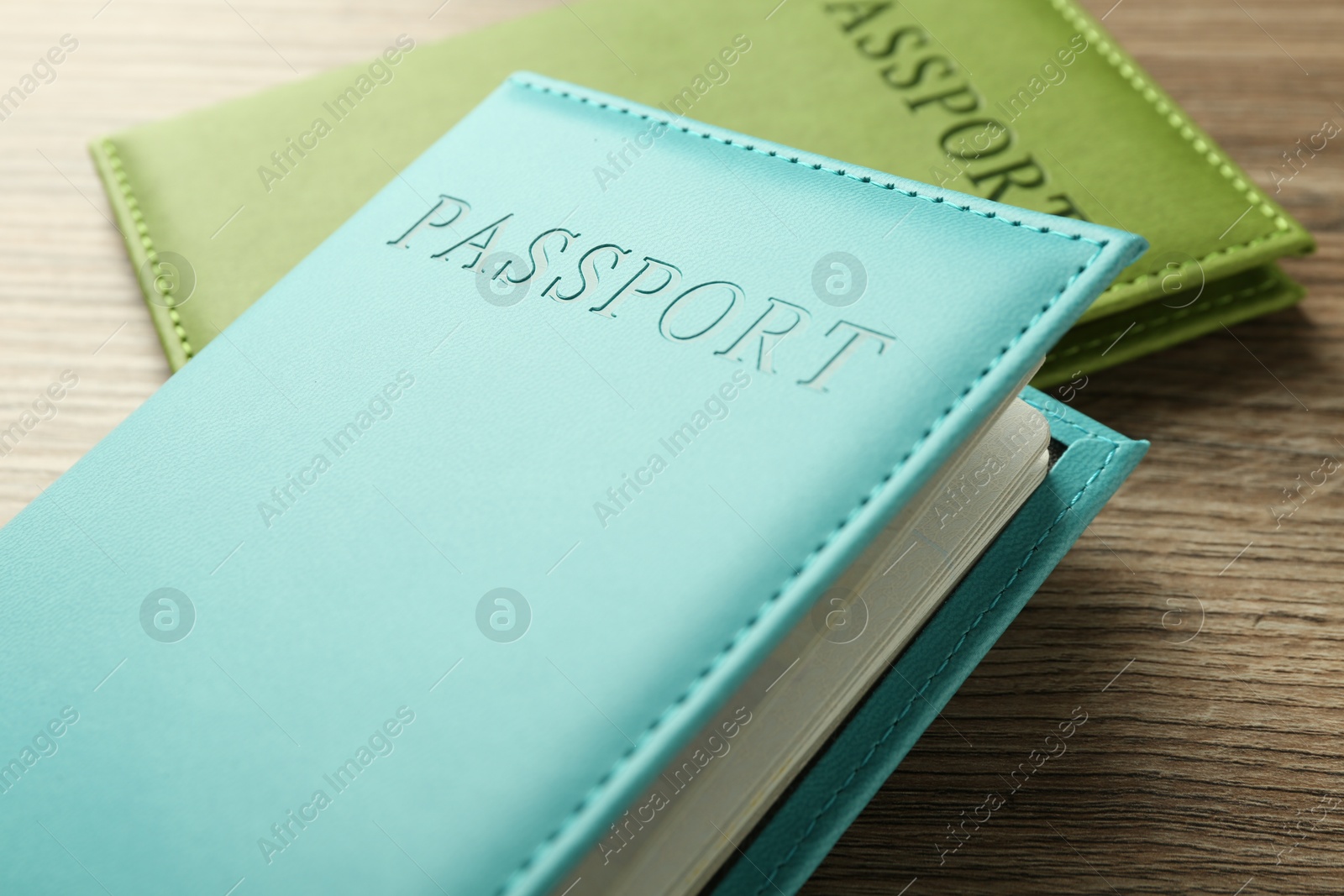 Photo of Two passports in bright covers on wooden table, closeup