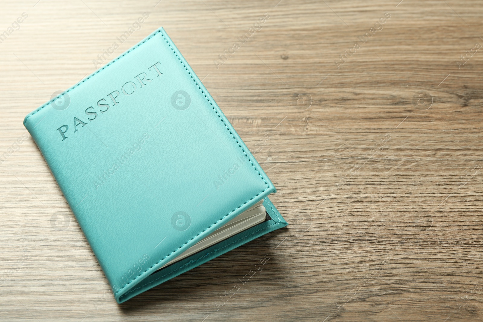 Photo of Passport in turquoise cover on wooden table, space for text