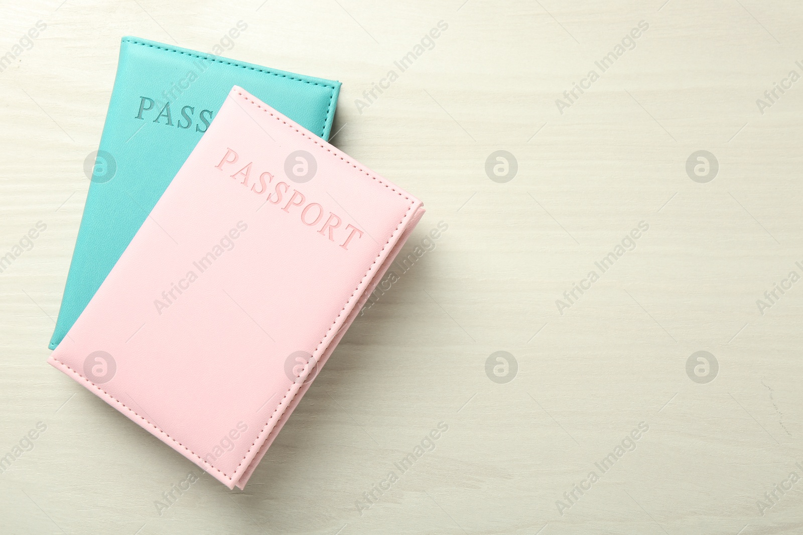 Photo of Two passports in bright covers on white wooden table, top view. Space for text