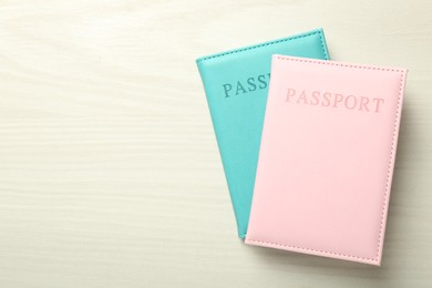 Photo of Two passports in bright covers on white wooden table, top view. Space for text