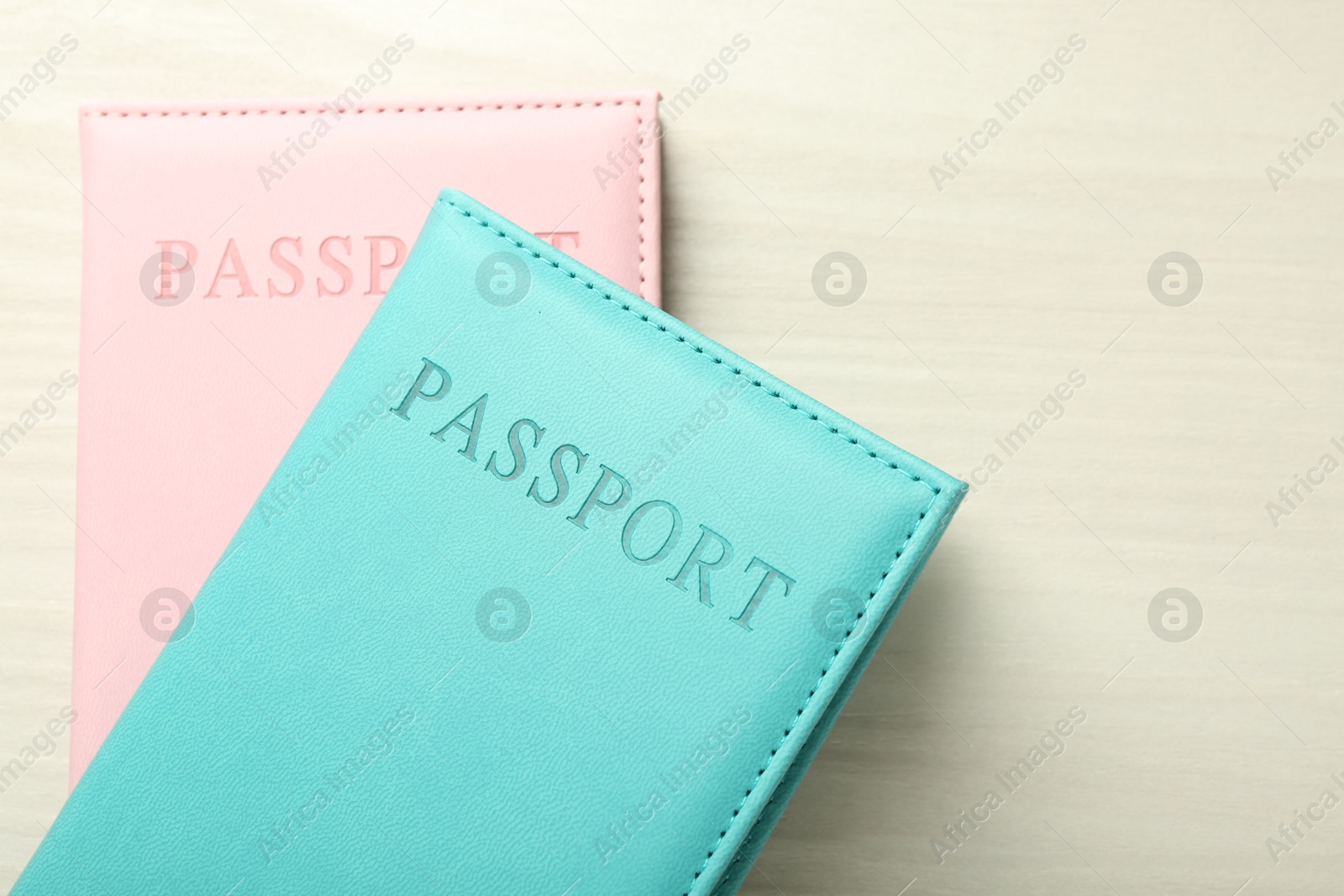 Photo of Two passports in bright covers on white wooden table, top view. Space for text