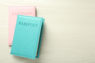 Photo of Two passports in bright covers on white wooden table, top view. Space for text