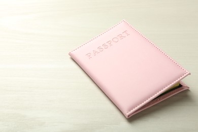 Photo of Passport in pink cover on white wooden table, closeup. Space for text