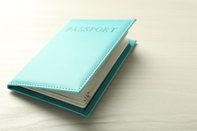 Photo of Passport in turquoise cover on white wooden table, closeup. Space for text