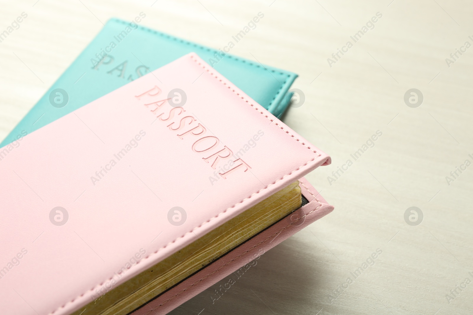 Photo of Two passports in bright covers on white wooden table, closeup