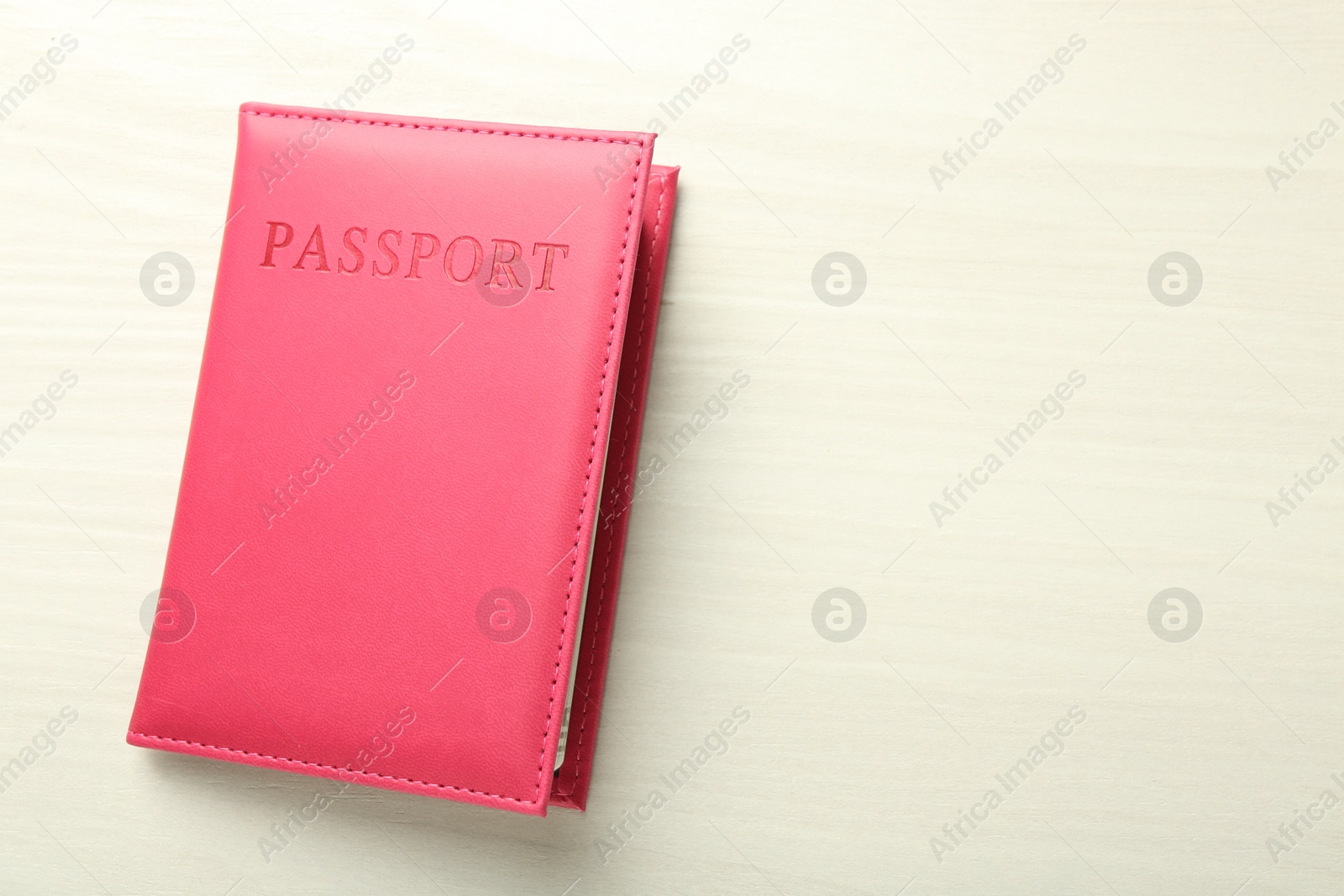 Photo of Passport in bright pink cover on white wooden table, top view. Space for text