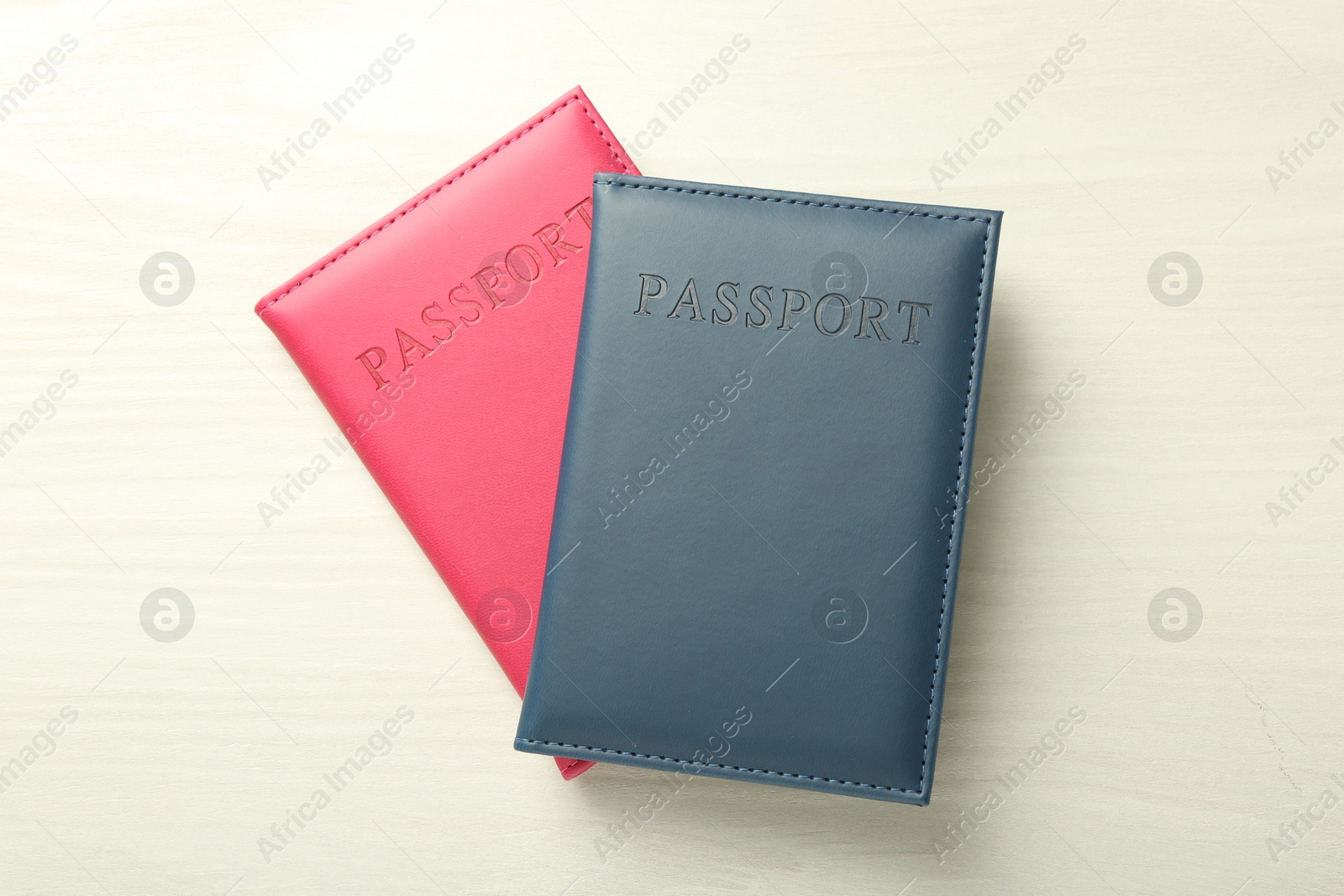 Photo of Two passports in bright covers on white wooden table, top view