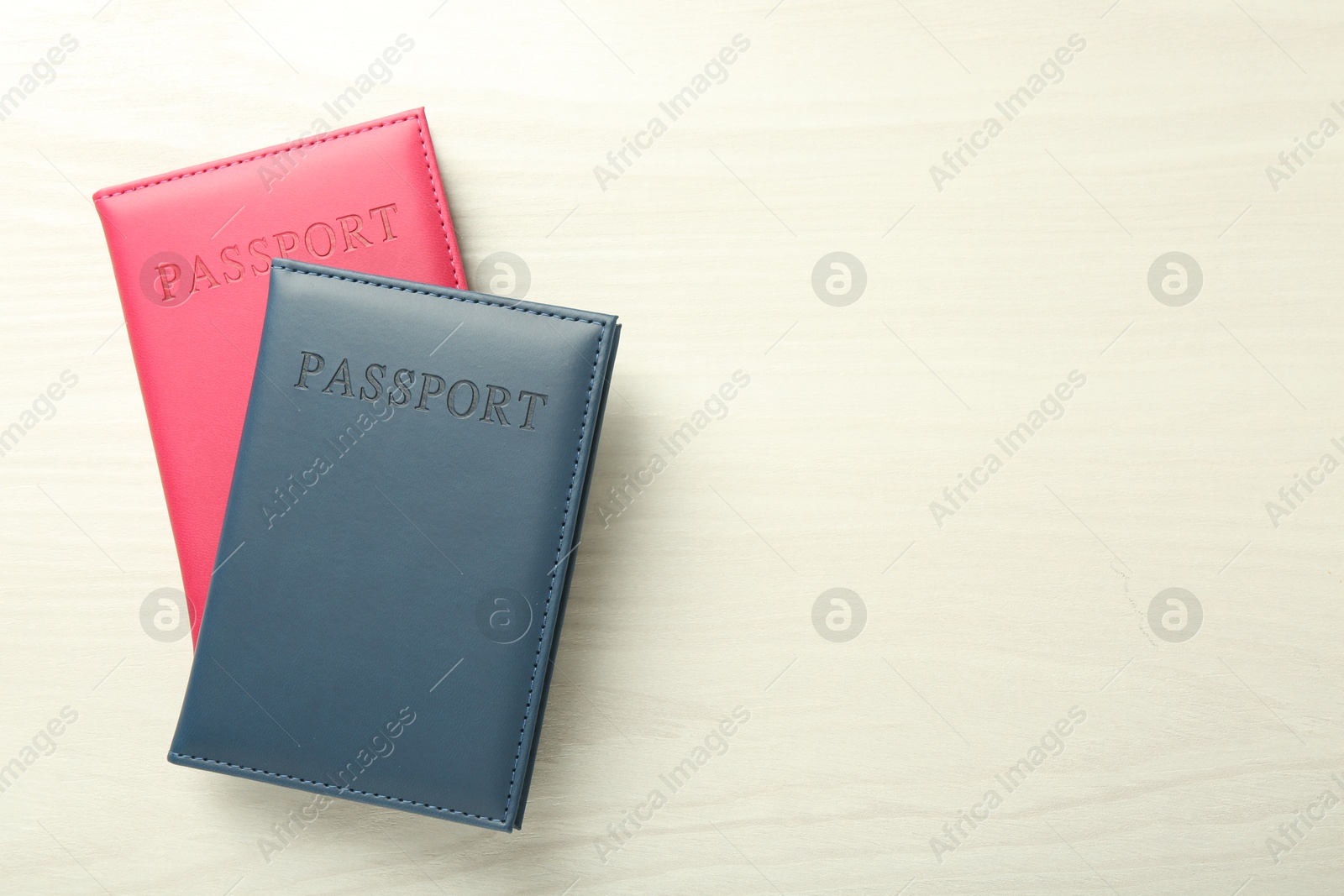 Photo of Two passports in bright covers on white wooden table, top view. Space for text