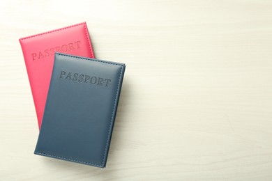 Photo of Two passports in bright covers on white wooden table, top view. Space for text