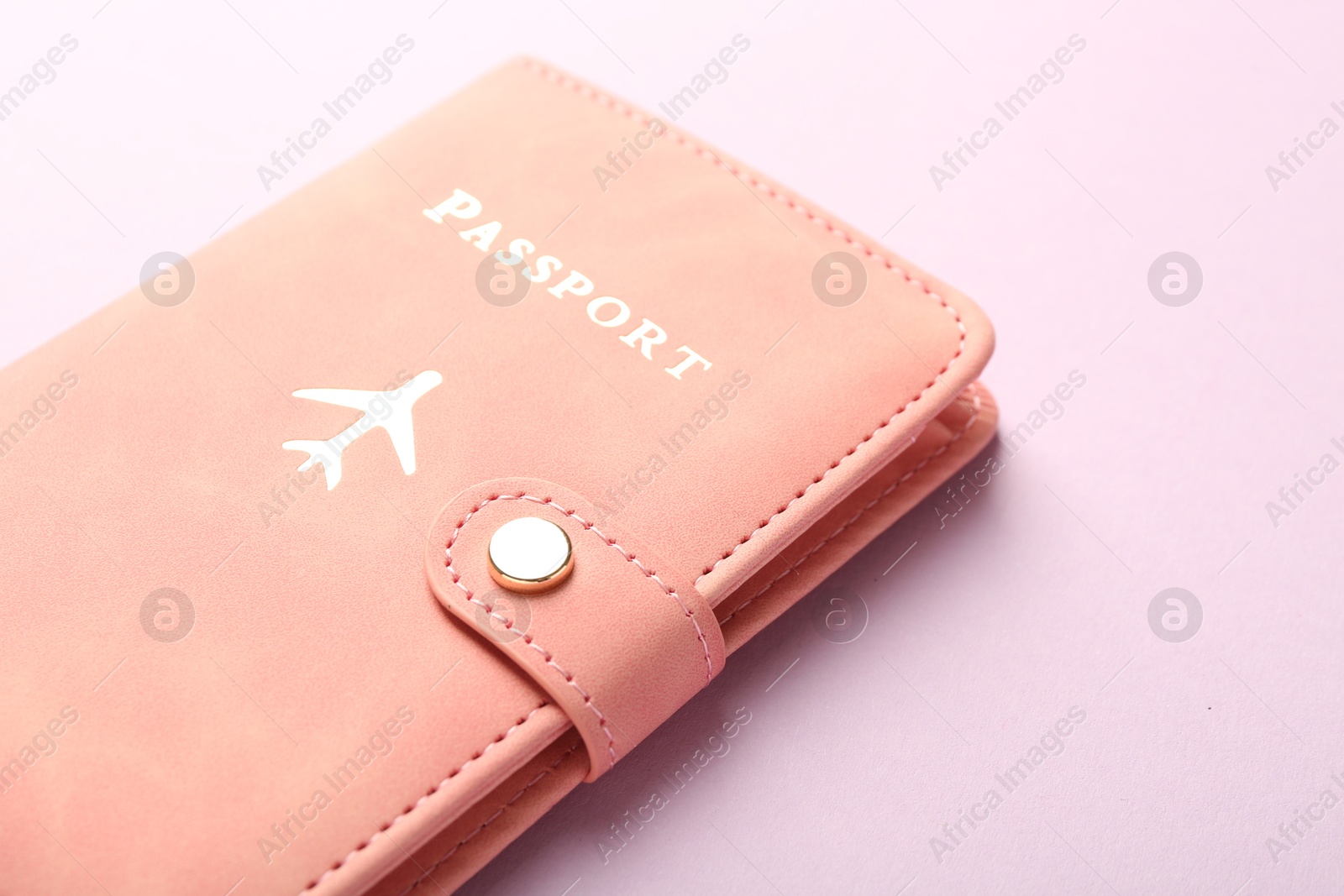 Photo of Passport in pink cover on violet background, closeup