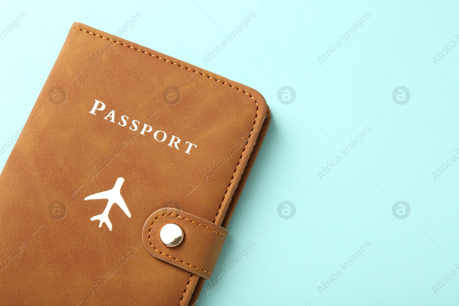 Photo of Passport in brown cover on turquoise background, top view. Space for text