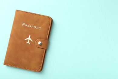 Photo of Passport in brown cover on turquoise background, top view. Space for text