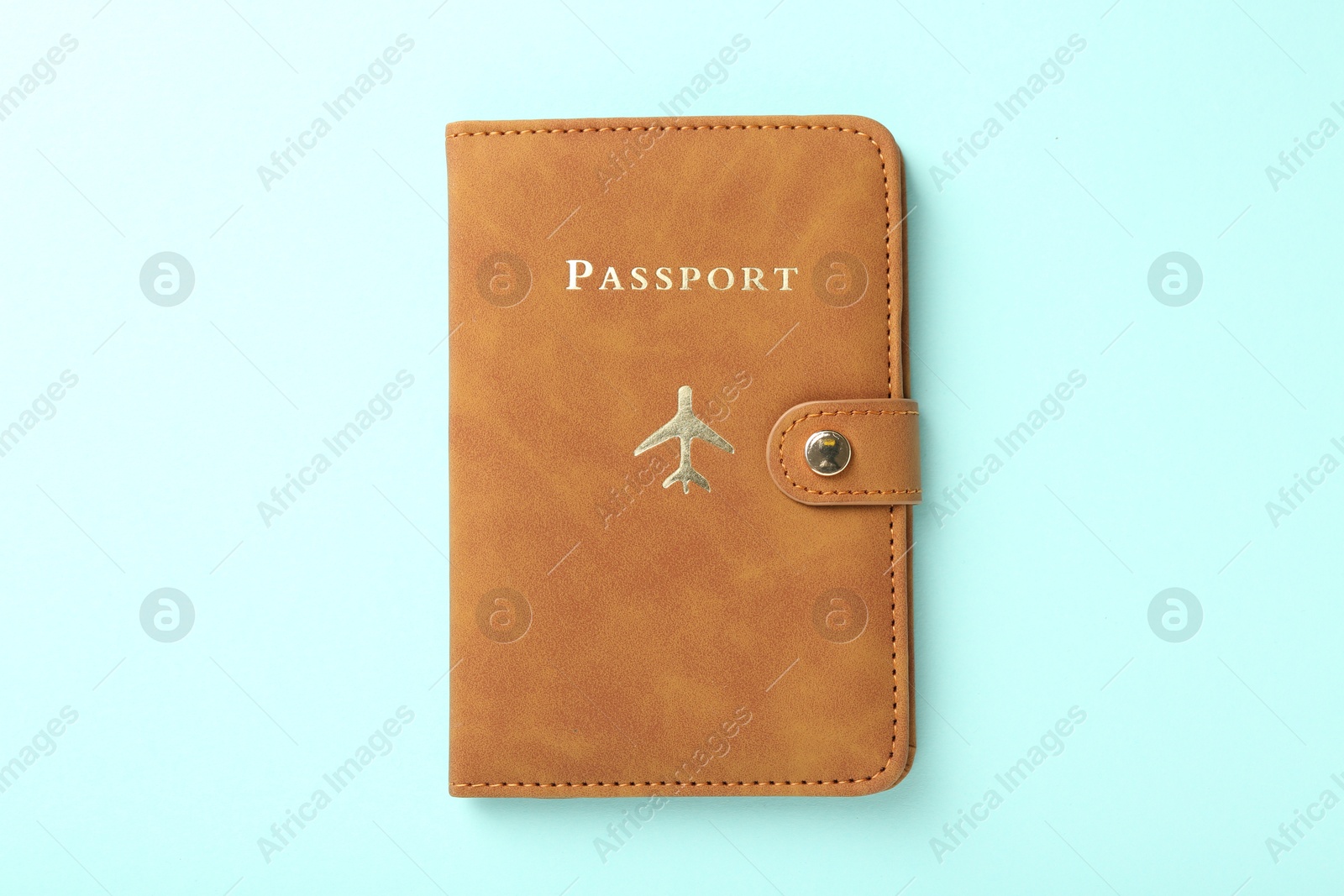 Photo of Passport in brown cover on turquoise background, top view