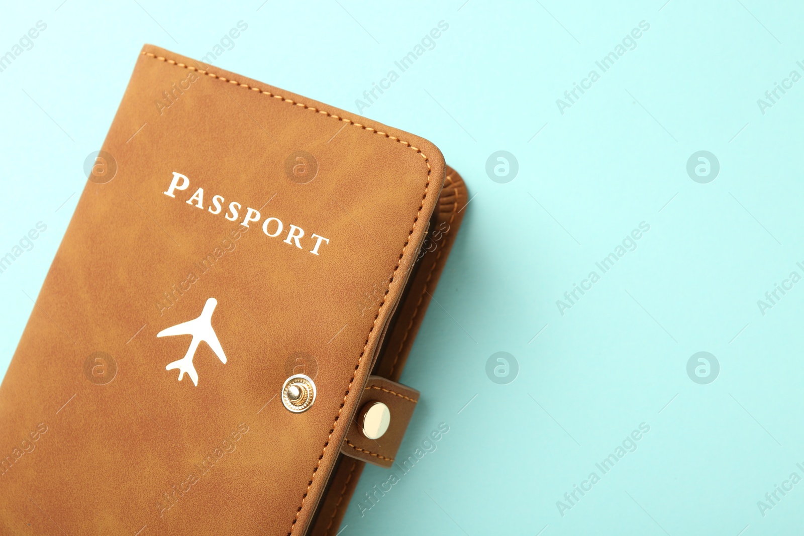 Photo of Passport in brown cover on turquoise background, top view. Space for text