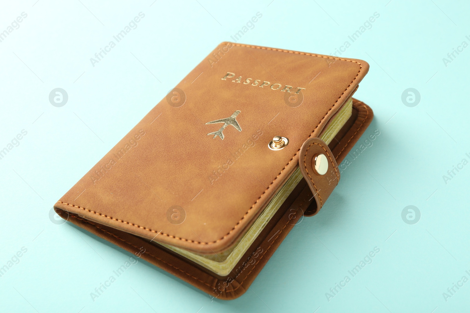 Photo of Passport in brown cover on turquoise background, closeup