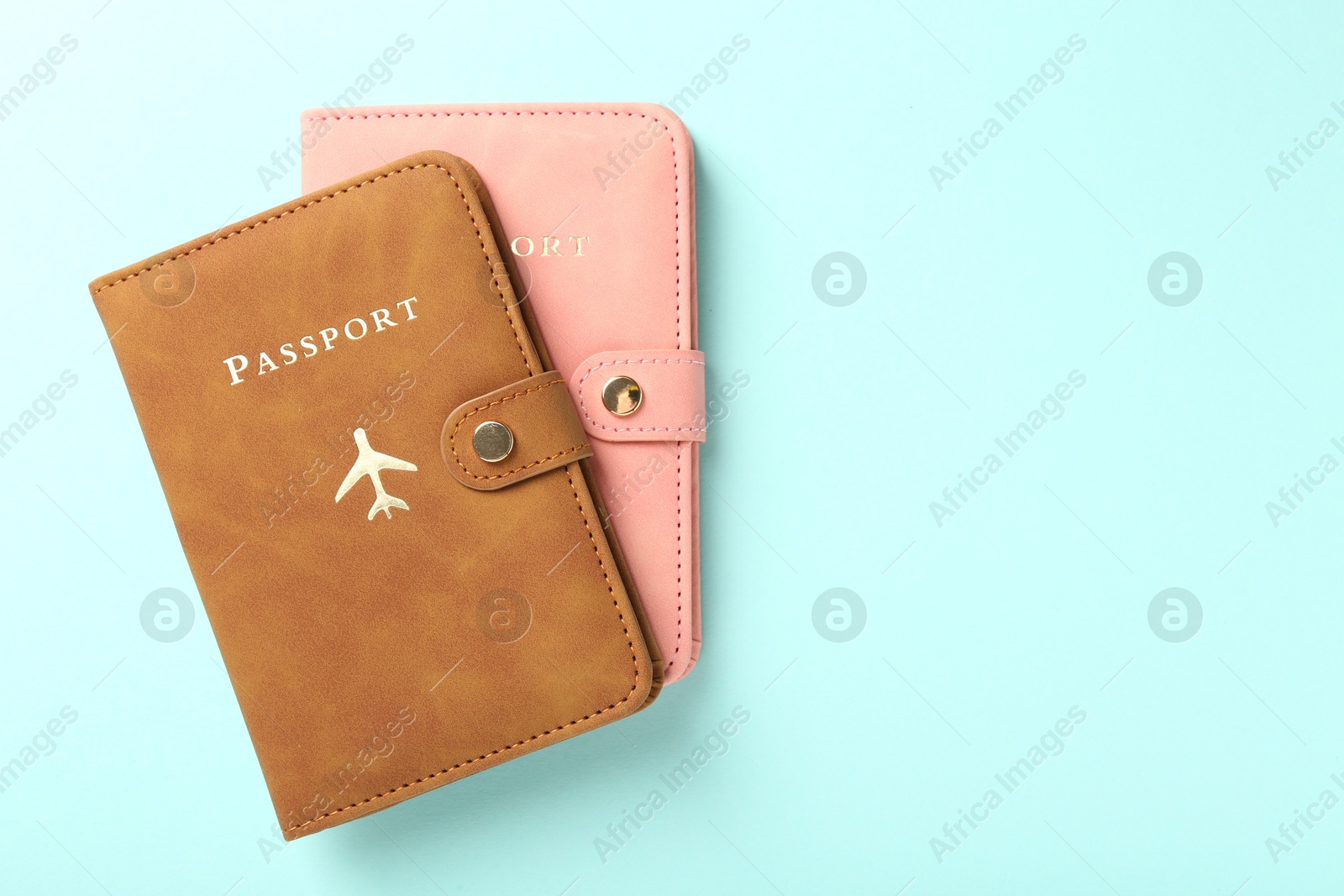 Photo of Two passports in bright covers on turquoise background, top view. Space for text